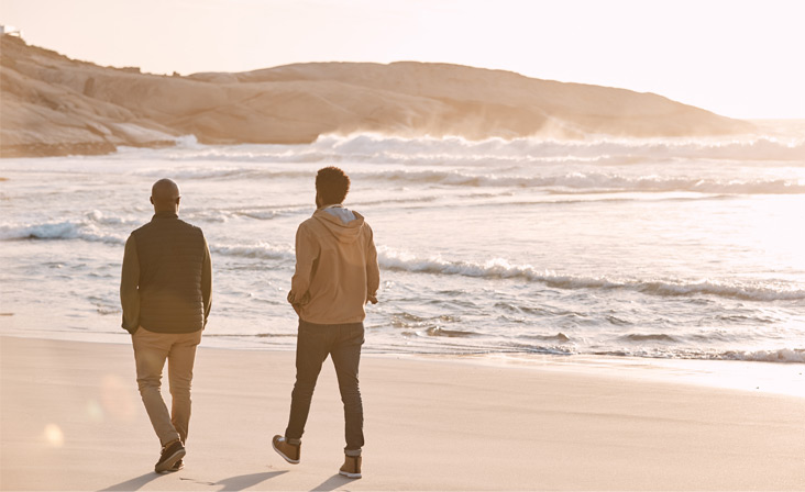 Immagine di due uomini che camminano sulla spiaggia