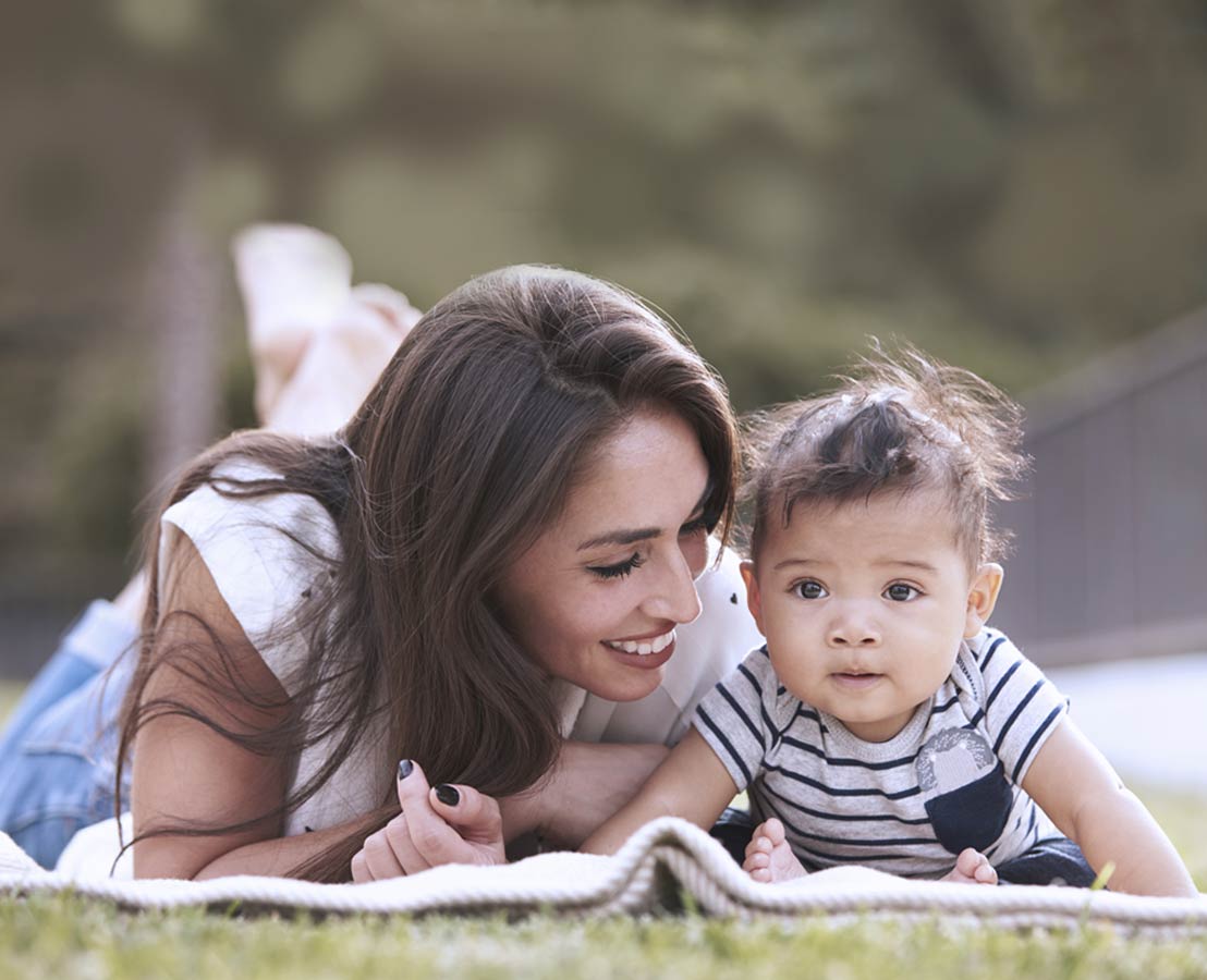 Immagine di madre con figlia sdraiate sul prato