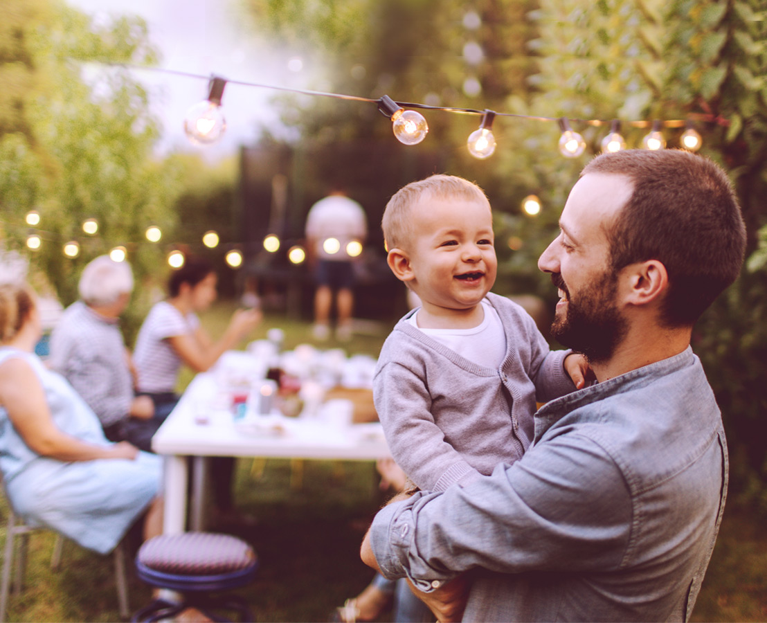 Immagine di padre con figlio in braccio durante una festa