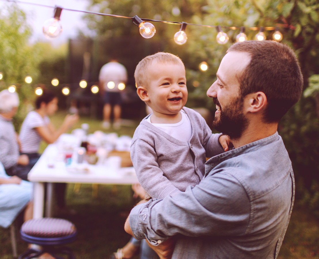 Immagine di padre con figlio in braccio durante una festa